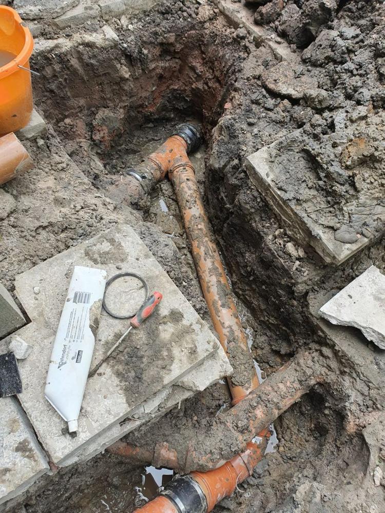 Drain repair with a new junction and couplings fitted in an excavation